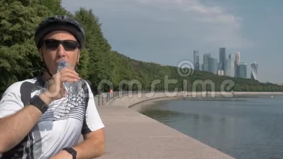 中年男子骑自行车头盔戴太阳镜从瓶子里喝水视频的预览图