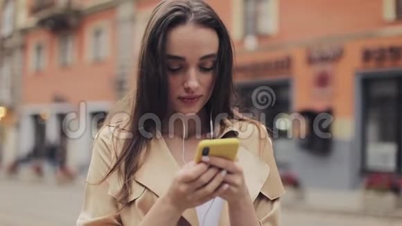 年轻迷人的微笑女人用她的智能手机站在老城街传播概念视频的预览图
