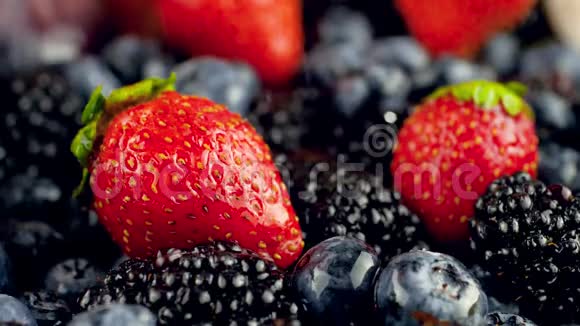 宏观慢动作视频水滴落在新鲜美味的草莓蓝莓和黑莓躺在桌子上视频的预览图