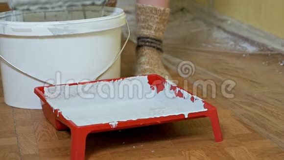 女孩用白色油漆在平底锅里浸泡一个建筑滚筒房间内的自我修复视频的预览图