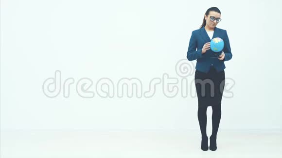 年轻的商业女性站在白色的背景上在地球仪的手中握住并挥动他的头扭曲着它视频的预览图