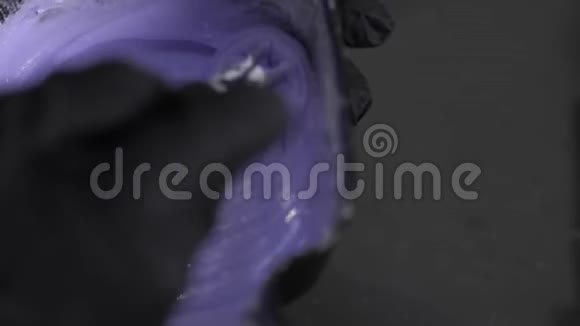 理发师把蓝色紫色的染发剂混合在一个黑色的碗里视频的预览图