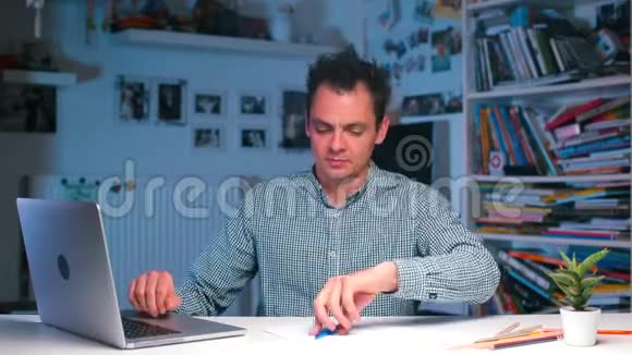 一个商人坐在办公桌前写字同时在笔记本电脑上工作视频的预览图