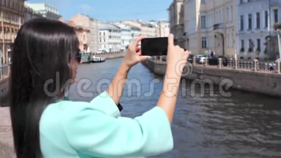 微笑旅游妇女在欧洲城市中欣赏水上运河和城市景观拍摄视频视频的预览图