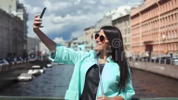 微笑旅游时尚女性自拍使用智能手机站在桥上的河流视频的预览图