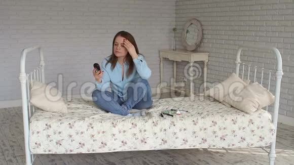 一个悲伤的女人坐在床上手里拿着血糖仪高血糖视频的预览图
