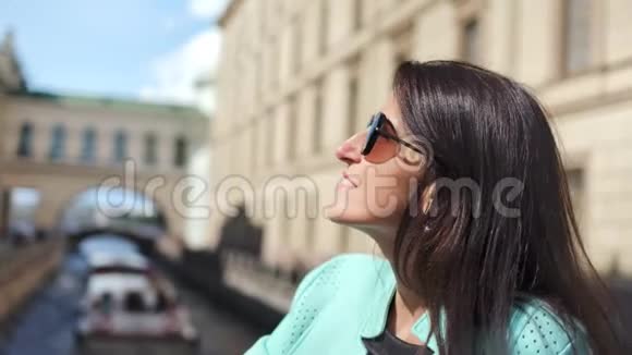 迷人的微笑时尚女性在城市水渠享受阳光背景是船视频的预览图