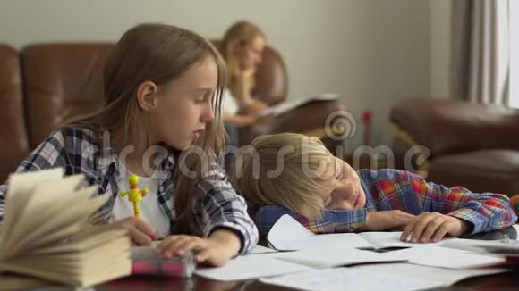 两个可爱的学龄儿童在家中的前景而他们的母亲坐在后台哥哥视频的预览图