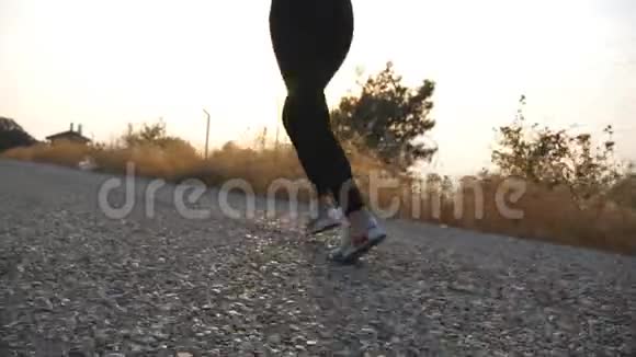 年轻活泼的女孩在乡间小路上慢跑背景是日出女性的腿在户外跑步运动型妇女视频的预览图