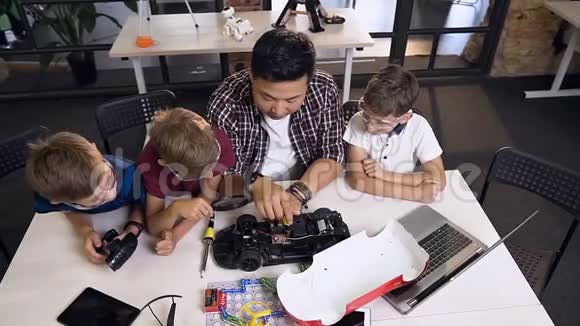 教师与幼儿一起尝试用电机样机修理电脑板的俯视图视频的预览图