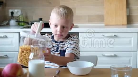 可爱的男孩4岁在家里的桌子上吃早餐玉米片和牛奶视频的预览图
