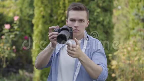 年轻的专业男性摄影师在户外用相机拍照的肖像摄影专业视频的预览图