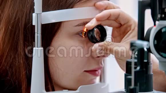 眼科医生眼科医生正在用一个特殊的放大镜观察女性的视力视频的预览图