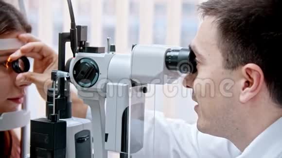 眼科医生医生正在用一个特殊的放大镜观察女性的视力视频的预览图