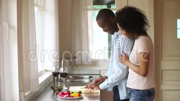 快乐的非洲妻子拥抱丈夫准备健康的晚餐视频的预览图
