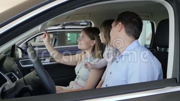 年轻家庭检查汽车沙龙家庭选择汽车父母视频的预览图