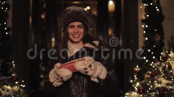 微笑少女的肖像看着幸福手捧礼盒站在落雪的户外圣诞视频的预览图