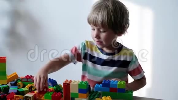可爱的男孩4岁在家里的桌子上玩五颜六色的塑料玩具砖视频的预览图