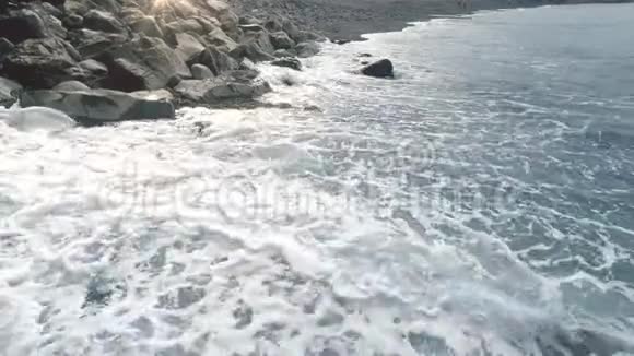 4k彩色视频海浪在海滩上的黑色火山沙和岩石上滚动和制动视频的预览图