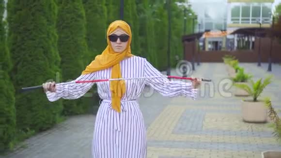 有魅力的年轻穆斯林妇女在公园里用拐杖走路视障视频的预览图