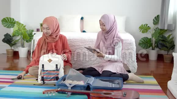 年轻美丽的穆斯林妇女和女朋友检查旅行物品视频的预览图