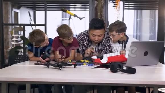 一队年轻的电子工程师和韩国老师使用螺丝刀同时在样品机器人中工作焊锡线视频的预览图