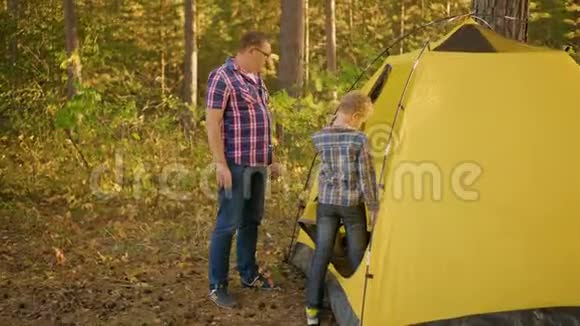 在美丽的森林里有一个孩子在黄色帐篷附近视频的预览图
