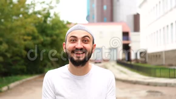 英俊的快乐胡子穆斯林男子在城市与惊讶的情绪令人惊讶的被年轻人震惊的情绪视频的预览图