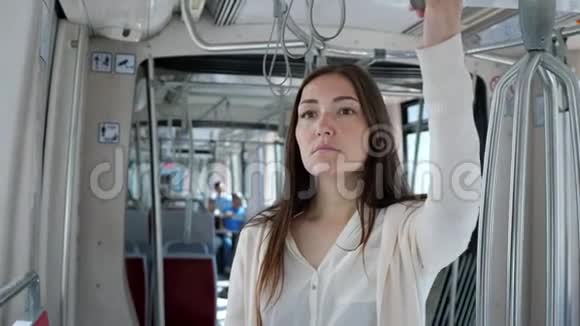女士手持扶手站在电车里进城视频的预览图