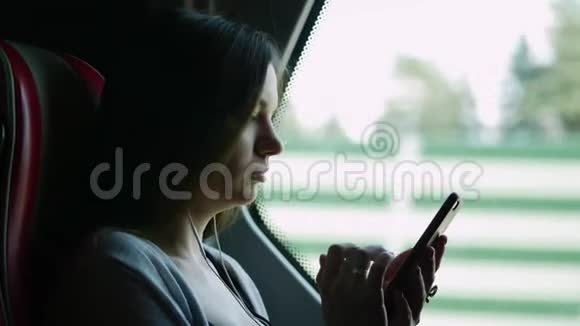 在公共汽车旅行听音乐和使用手机中孤独女性的特写肖像视频的预览图