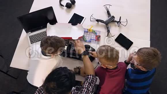 三名学生的俯视图中有一名教师试图用一台电机的原型修理电脑板视频的预览图