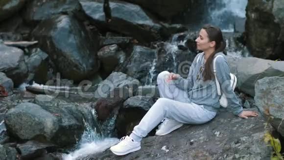 在瀑布附近享受大自然的女人视频的预览图
