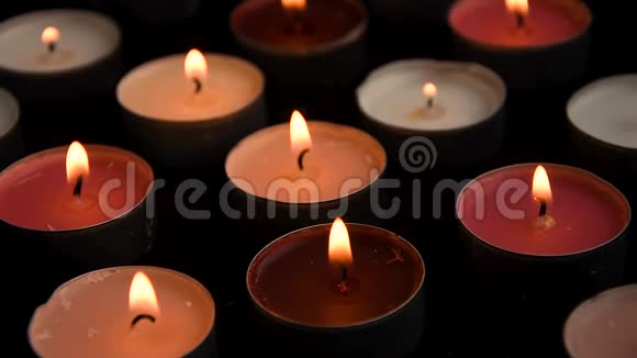 在黑色背景下点燃的茶光蜡烛聚在一起浪漫气氛视频的预览图