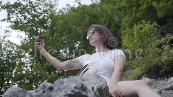 白人女性游客把自拍带到山上的岩石上视频的预览图