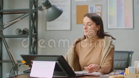 一个年轻的设计师女孩使用一个带有大窗口的办公室的工作站在一个现代的图形屏幕上创建标识视频的预览图