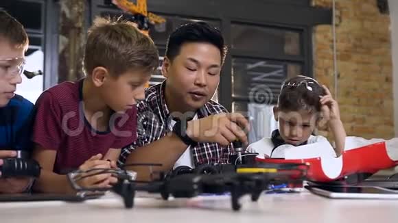 亚洲电子工程师带着白种人的学童在现代学校实验室工作测试电动汽车模型视频的预览图
