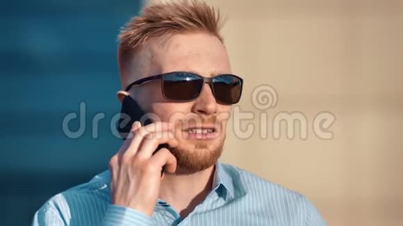 特写脸自信成功留胡子的男士戴墨镜讨论使用智能手机做生意视频的预览图