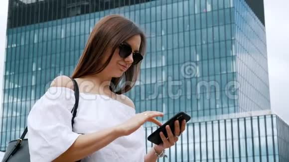 自信的女商人在建筑物的背景下使用手机视频的预览图