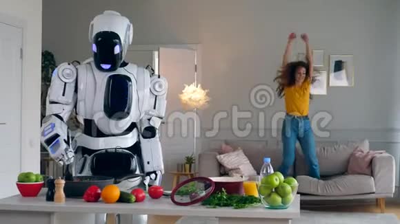 快乐的女孩跳上沙发而机器人做饭视频的预览图