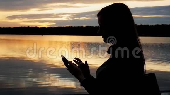 一位女游客的剪影一位女士在傍晚日落时走在湖上的一座桥上视频的预览图