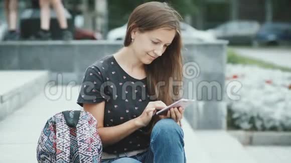 坐在楼梯上用智能手机的女人视频的预览图