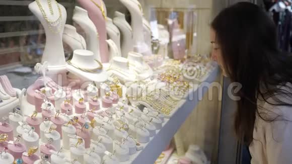 女孩看着昂贵的珠宝在商店里做出选择视频的预览图