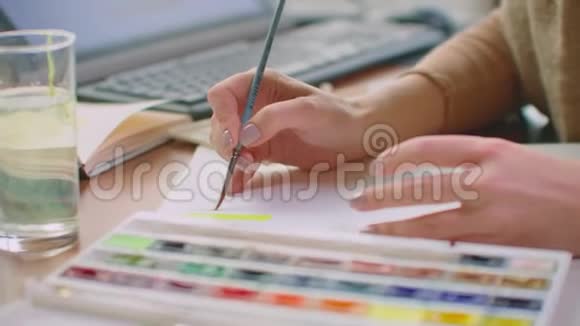 一个年轻的女人用刷子和油漆选择一个合适的阴影为标志设计或墙壁颜色和阴影的选择视频的预览图
