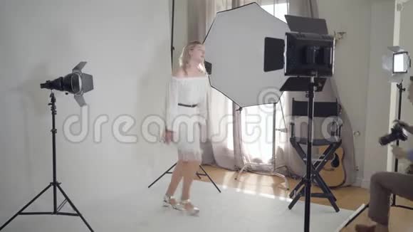 拍摄的后台专业摄影师拍摄优雅的女人跳舞和在白色上旋转的照片视频的预览图