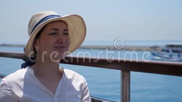 戴着优雅草帽的漂亮女人坐在甲板上视频的预览图