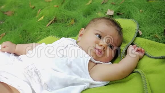 小女孩躺在公园草地上的地毯上梦幻般的新生婴儿躺在户外草地上视频的预览图