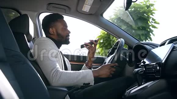 快乐快乐的非裔美国人坐在他买的车的前座上打电话视频的预览图