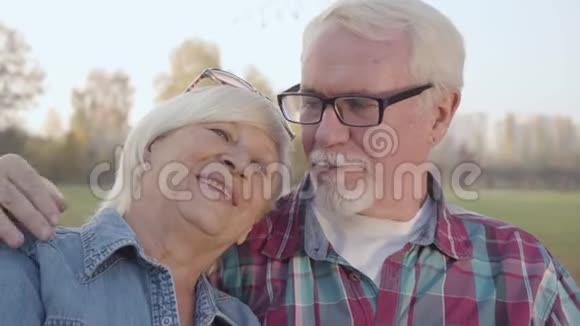 一个快乐的白人退休家庭在阳光下坐在长凳上聊天的特写肖像成熟的欧洲视频的预览图