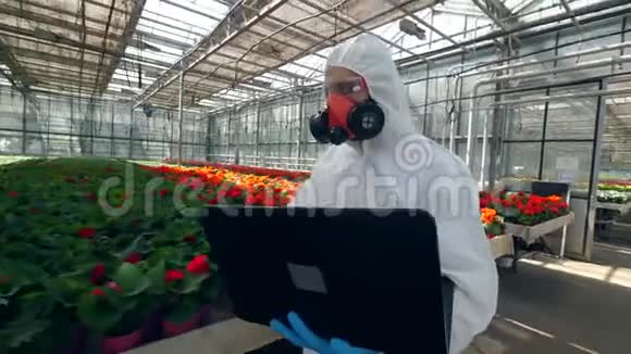 一位带着笔记本电脑的男生物学家正沿着盛开的花朵散步视频的预览图