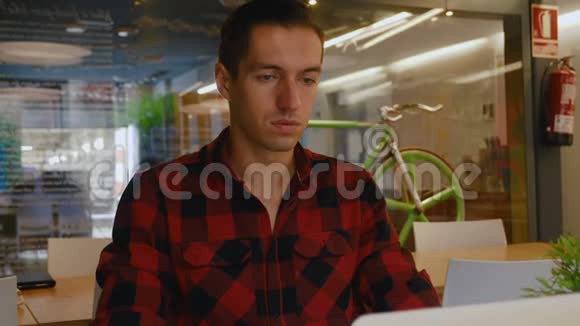 穿格子衬衫的年轻商人在同事办公室的笔记本电脑工作视频的预览图